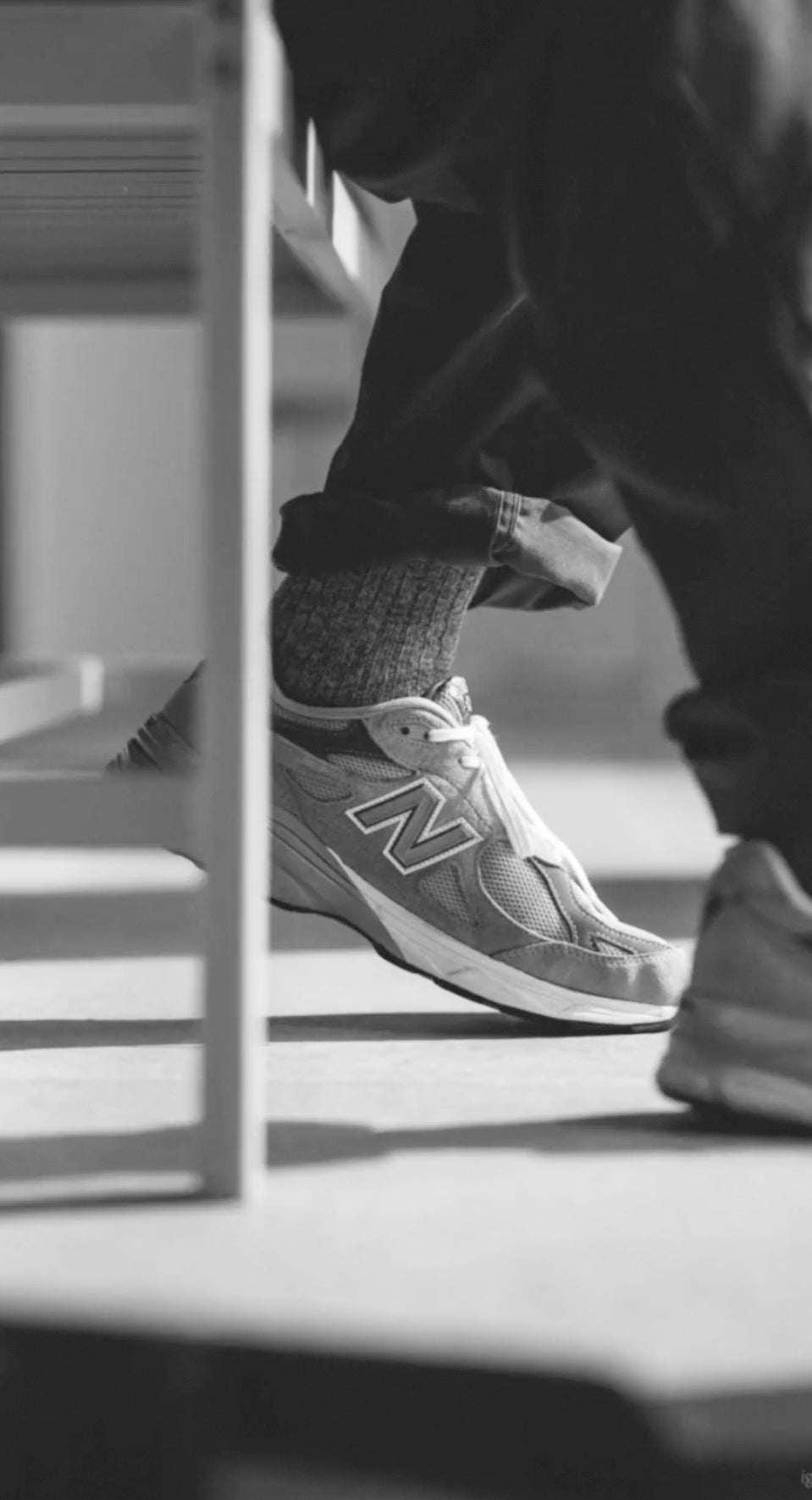 Person wearing a New Balance sneaker paired with black/grey melange heavy knitted socks from Democratique